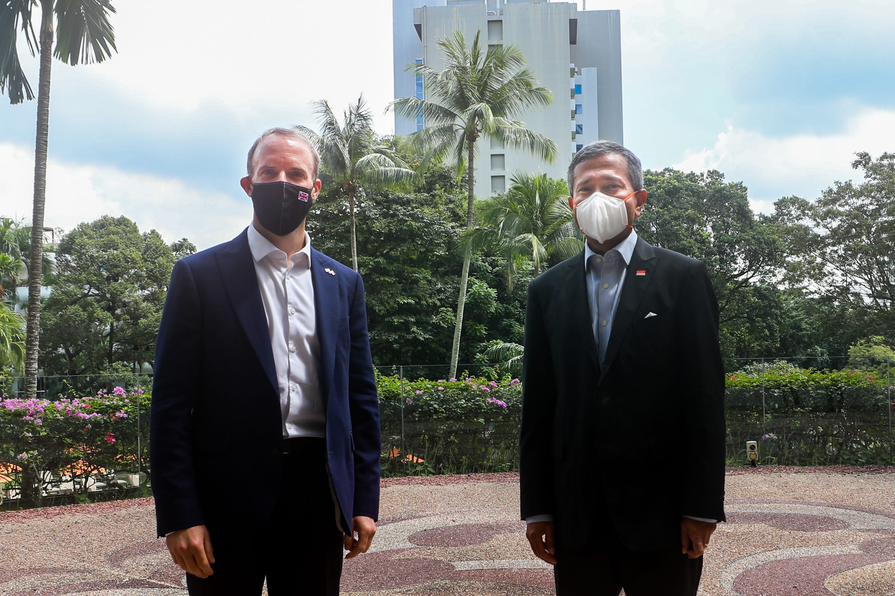 People in business attire sit at a set table with water bottles and menus.